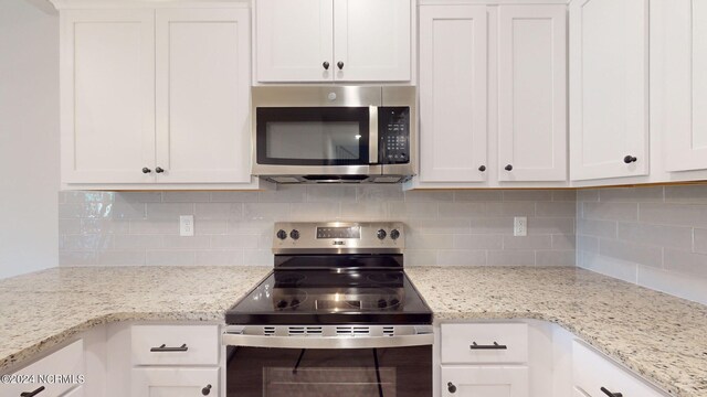 kitchen featuring appliances with stainless steel finishes, white cabinetry, decorative backsplash, and light stone countertops