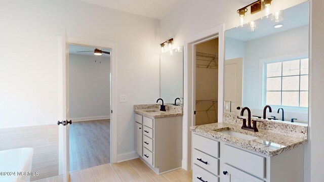 bathroom with two vanities, a sink, and a spacious closet