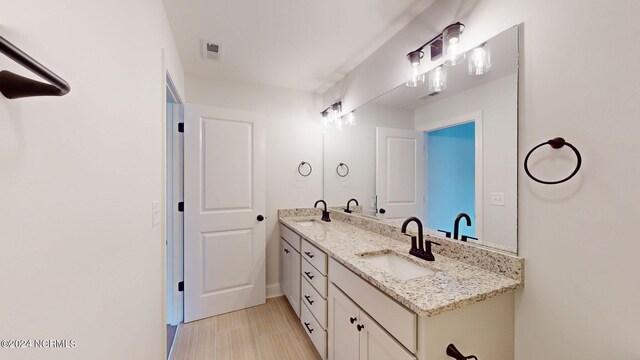 bathroom with double vanity, visible vents, and a sink