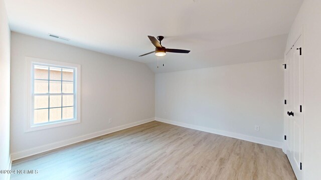 unfurnished room featuring lofted ceiling, visible vents, light wood-style floors, ceiling fan, and baseboards