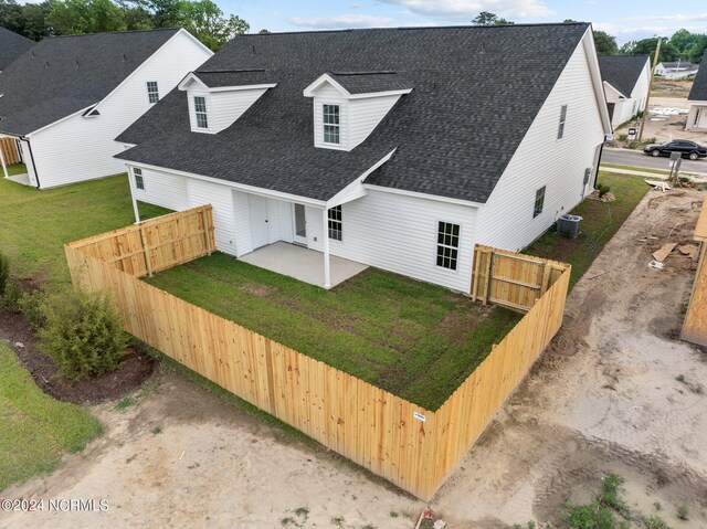 view of front of property with a patio, roof with shingles, fence private yard, cooling unit, and a front lawn