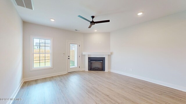 unfurnished living room with a fireplace, baseboards, wood finished floors, and recessed lighting