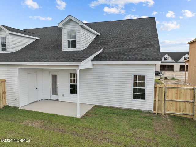 back of property featuring a yard, roof with shingles, a patio area, and fence