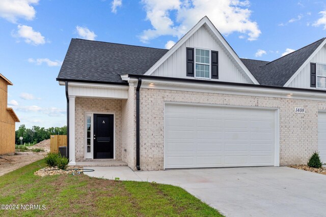 view of front of property with board and batten siding, roof with shingles, driveway, and brick siding