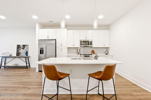 383 James St, Vass, NC 28394 - kitchen featuring a breakfast bar, a kitchen island with sink, tasteful backsplash, white cabinetry, and stainless steel appliances
