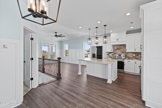 kitchen featuring hanging light fixtures, a center island, stainless steel appliances, and white cabinets