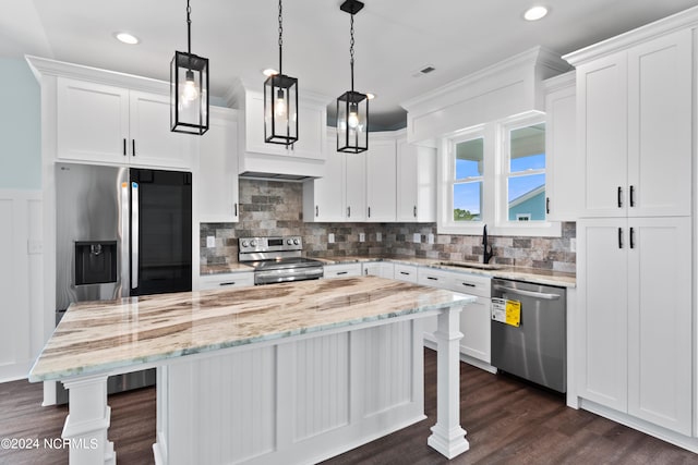 kitchen featuring hanging light fixtures, dark wood-type flooring, white cabinetry, appliances with stainless steel finishes, and a center island