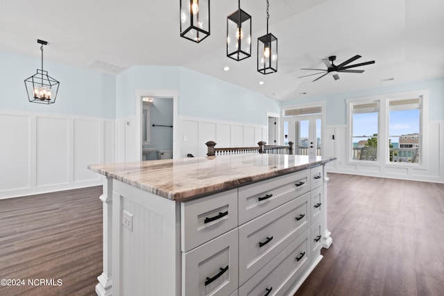 kitchen featuring pendant lighting, a kitchen island, white cabinetry, dark hardwood / wood-style floors, and light stone countertops