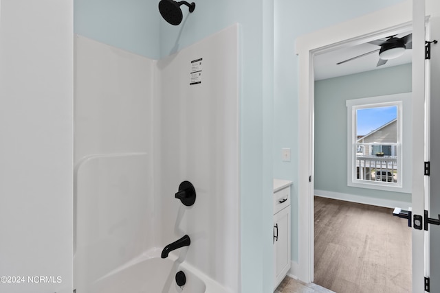 bathroom with washtub / shower combination, hardwood / wood-style floors, vanity, and ceiling fan