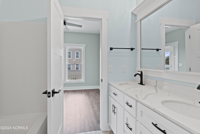 bathroom featuring wood-type flooring, vanity, a tub to relax in, and ceiling fan