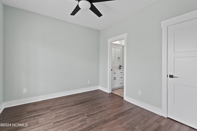 unfurnished bedroom featuring ceiling fan, ensuite bath, and dark wood-type flooring