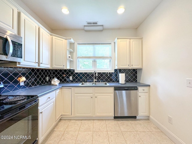 kitchen featuring appliances with stainless steel finishes, light tile patterned flooring, decorative backsplash, and sink