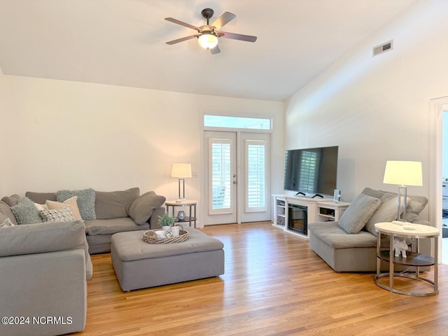 living room with ceiling fan, light hardwood / wood-style flooring, lofted ceiling, and a fireplace