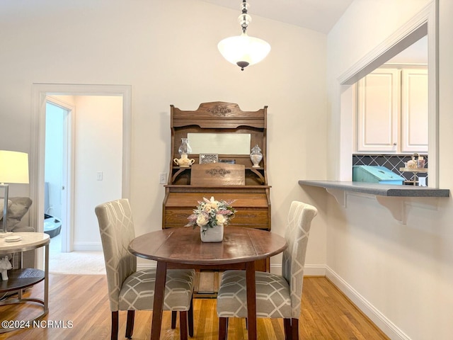 dining space with light wood-type flooring and lofted ceiling