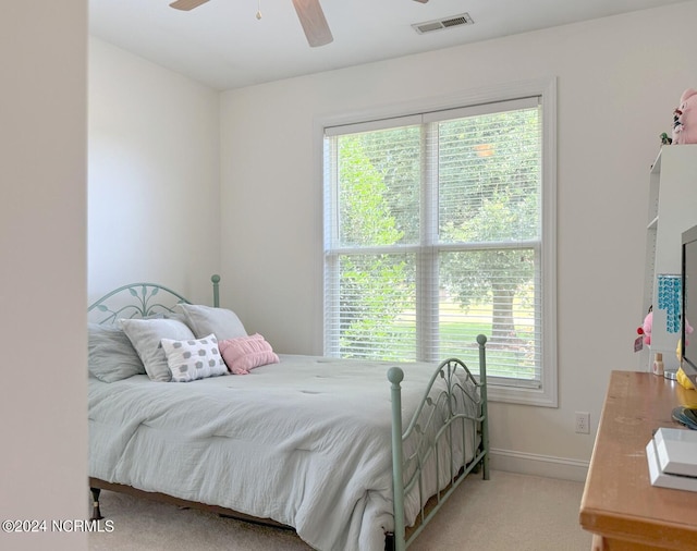 bedroom featuring ceiling fan, light carpet, and multiple windows