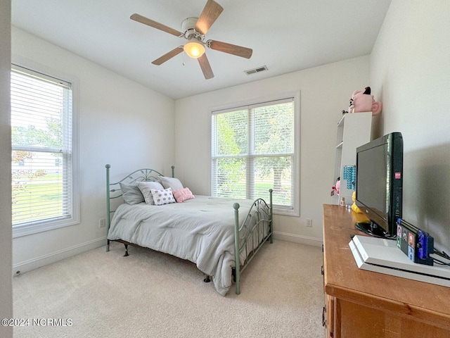 bedroom with multiple windows, light carpet, and ceiling fan