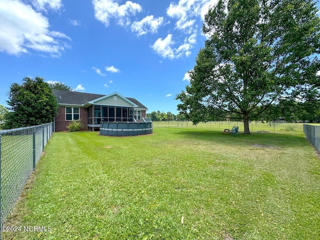 view of yard featuring a sunroom and a fenced in pool