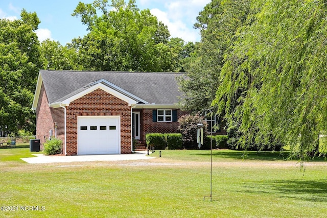 view of front of home featuring a front yard, central AC unit, and a garage