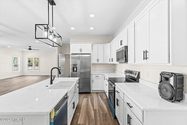 kitchen with a sink, white cabinets, appliances with stainless steel finishes, light stone countertops, and pendant lighting