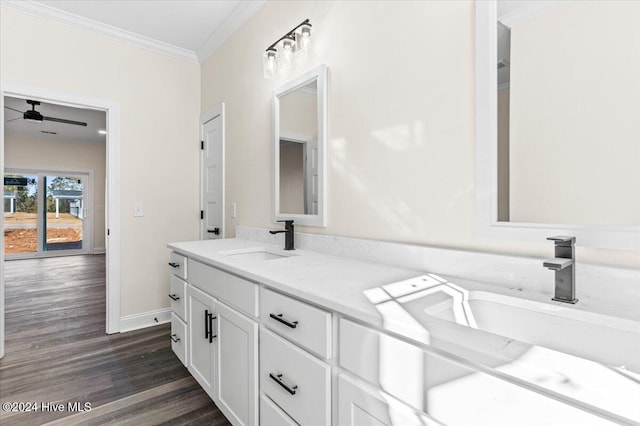 bathroom featuring crown molding, double vanity, a ceiling fan, a sink, and wood finished floors