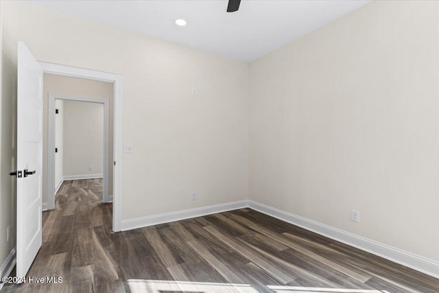 spare room featuring dark wood-style flooring, recessed lighting, and baseboards