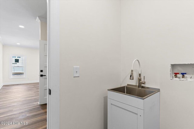 laundry room featuring crown molding, hookup for a washing machine, a sink, wood finished floors, and laundry area