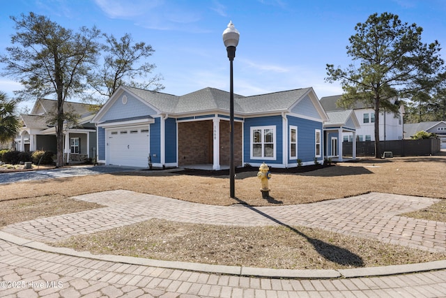 ranch-style house with decorative driveway, roof with shingles, and an attached garage