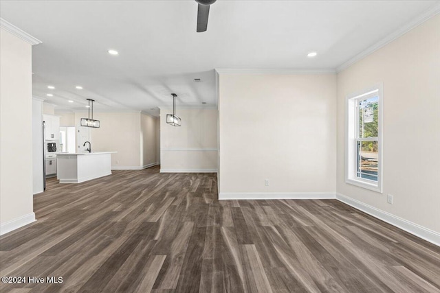 unfurnished living room with recessed lighting, a sink, baseboards, ornamental molding, and dark wood finished floors