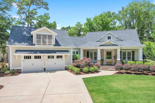 craftsman house with a front yard, a porch, and a garage