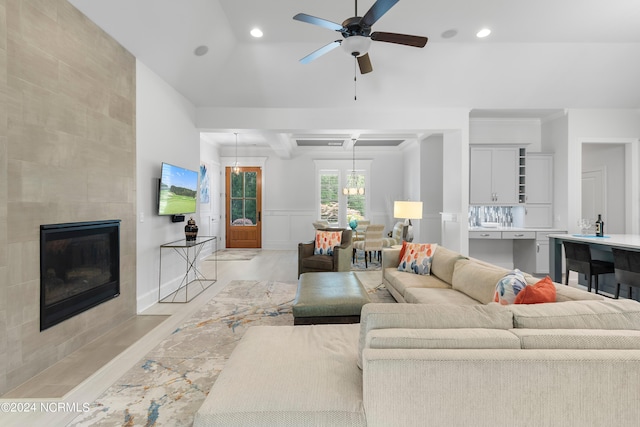 living room with beam ceiling, ceiling fan, a fireplace, and light hardwood / wood-style floors