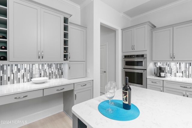 kitchen featuring double oven, gray cabinetry, tasteful backsplash, and ornamental molding