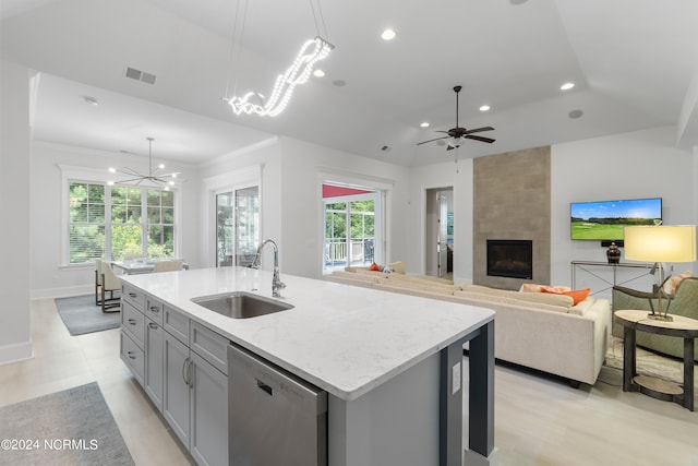 kitchen with a fireplace, sink, decorative light fixtures, dishwasher, and an island with sink