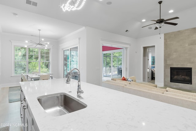 kitchen featuring light stone counters, sink, pendant lighting, a fireplace, and lofted ceiling