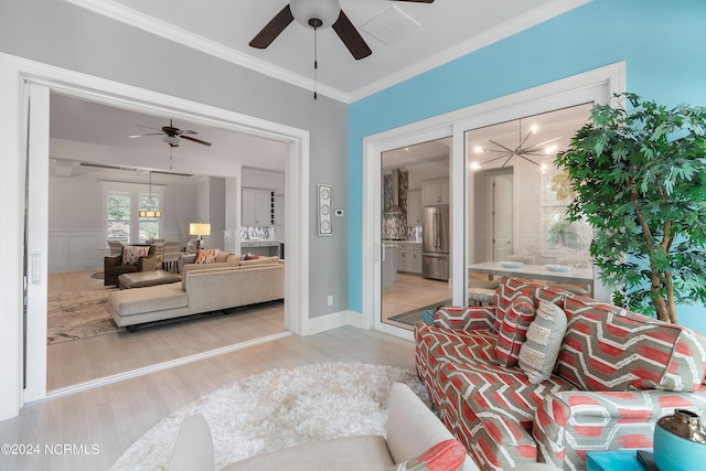 living room with ceiling fan, ornamental molding, and light wood-type flooring