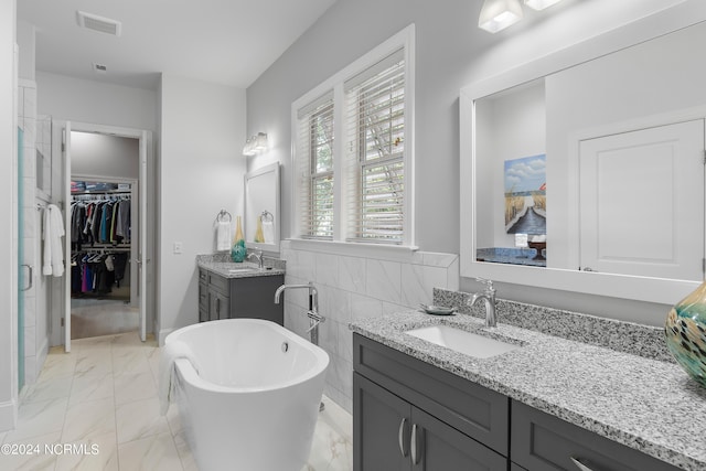 bathroom with a tub to relax in, vanity, and tile walls