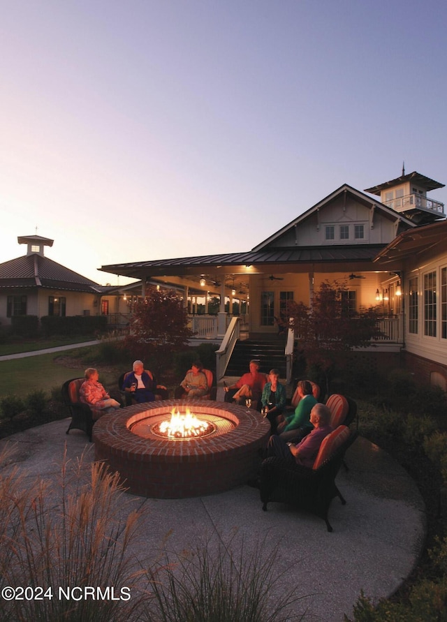 patio terrace at dusk with an outdoor fire pit and ceiling fan