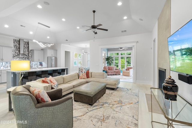 living room with ceiling fan, light hardwood / wood-style floors, and vaulted ceiling