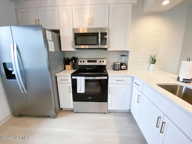 kitchen featuring appliances with stainless steel finishes, tasteful backsplash, white cabinetry, and sink