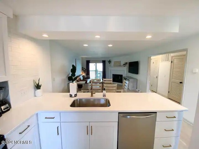 kitchen featuring dishwasher, kitchen peninsula, white cabinetry, and sink