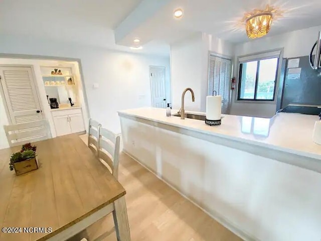 kitchen with sink, light hardwood / wood-style floors, and a notable chandelier