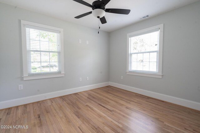 empty room with a wealth of natural light, ceiling fan, and light wood-type flooring