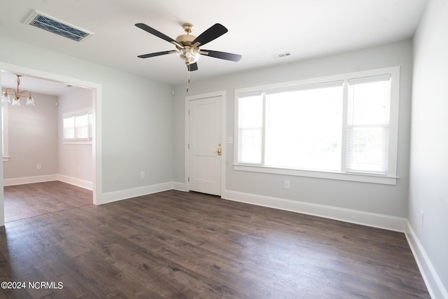 empty room with dark hardwood / wood-style floors and ceiling fan with notable chandelier