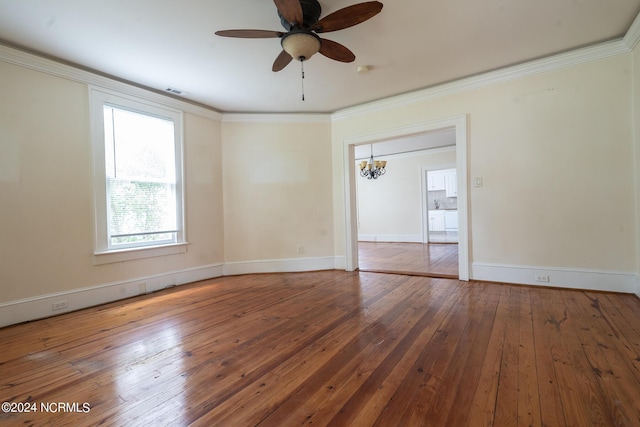 empty room featuring ornamental molding, wood-type flooring, and ceiling fan with notable chandelier