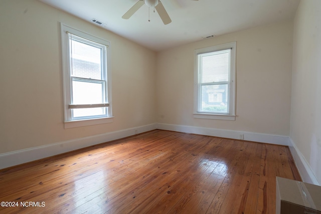 empty room featuring ceiling fan, a healthy amount of sunlight, and light wood-type flooring