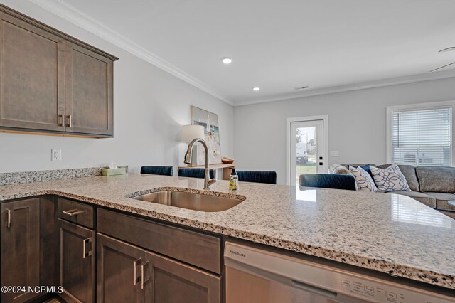 kitchen with stainless steel dishwasher, light stone countertops, dark brown cabinetry, a healthy amount of sunlight, and a sink