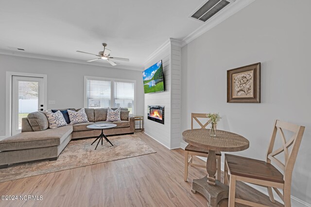living room featuring visible vents, ornamental molding, ceiling fan, light wood-style floors, and a fireplace
