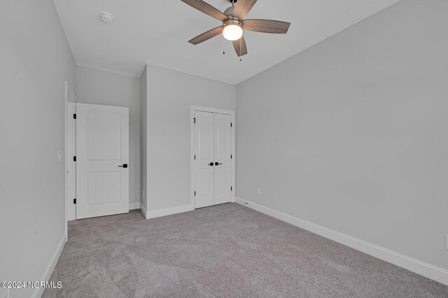 unfurnished bedroom with a closet, baseboards, a ceiling fan, and carpet floors