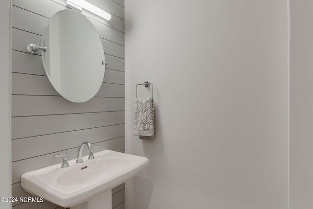 bathroom featuring wood walls and sink