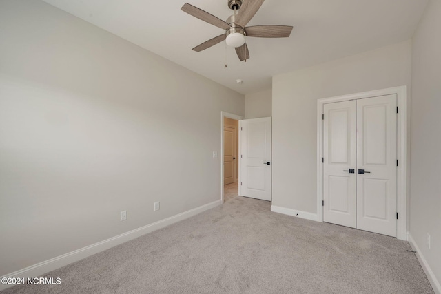 unfurnished bedroom with a closet, light colored carpet, and ceiling fan