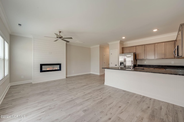 kitchen featuring light wood-type flooring, stainless steel appliances, ceiling fan, sink, and a fireplace